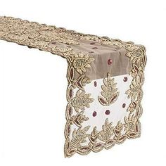 the table runner is decorated with gold and red flowers on white fabric, along with a brown lace edge