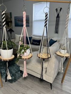 three hanging planters with plants in them on the floor next to a gray couch