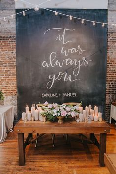 a table with candles and flowers on it in front of a chalkboard that says it was always you