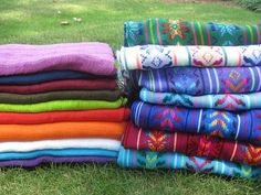 a pile of colorful towels sitting on top of a lush green field