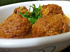 a white bowl filled with meatballs and garnished with parsley on top