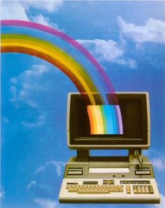 an old computer with a rainbow coming out of the screen in front of a blue sky