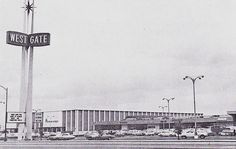 an old black and white photo of cars parked in front of a west gate store