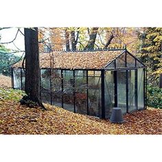 a small glass house surrounded by leaves and trees