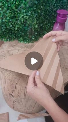 someone is making something out of cardboard and wrapping it in brown paper with their hands