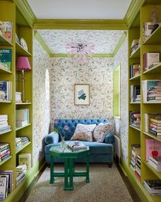 a living room filled with lots of green bookshelves next to a blue couch