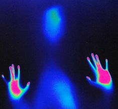 an image of two hands in the dark with neon blue and pink light on them