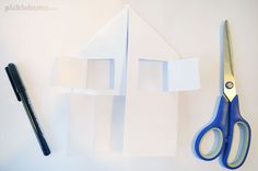 scissors and paper cut out to look like a house on top of a piece of white paper