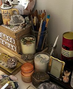 there are many items on the desk with pens and pencils in their containers, along with other things