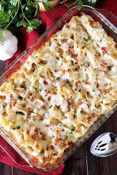 a casserole dish with cheese and vegetables on the side next to a spoon