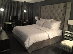 a large bed with white sheets and pillows in a bedroom next to a desk area