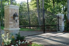 a gated entrance to a park with flowers in the foreground and trees in the background