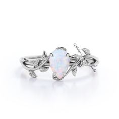 a white opal and diamond ring with leaves on it's sides, set in silver