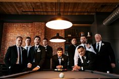 a group of men standing around a pool table