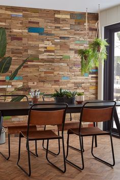 a dining room table with chairs and a potted plant next to it on top of a hard wood floor