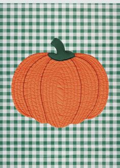 an orange pumpkin sitting on top of a green and white checkered table cloth