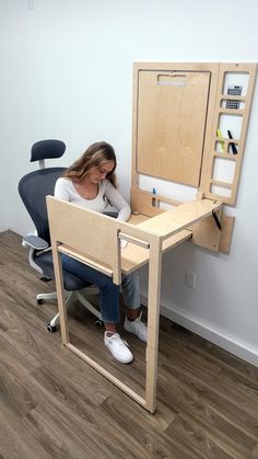 a woman sitting at a desk with a computer monitor and chair in front of her