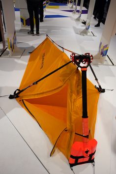 an orange tent sitting on top of a white floor next to a red object in front of it