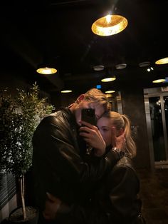 a man and woman embracing each other in front of a mirror with lights on the ceiling