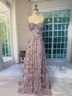 This handmade gown features an elegant lavender base adorned with vintage-inspired floral prints, exuding a sense of romantic charm. The delicate spaghetti straps and ruched bodice accentuate the feminine silhouette, while the tiered ruffle details on the skirt add a touch of playful movement. Perfect for outdoor weddings, evening events, or special occasions, this gown is sure to make you the center of attention. The lace-up back not only enhances the vintage appeal but also allows for a custom Spaghetti Strap Gown, Purple Floral Dress, Lavender Floral, Outdoor Weddings, Ruched Bodice, Feminine Silhouette, Floral Ruffle, Corset Dress, Dress Clothes For Women