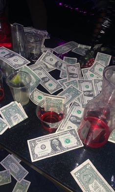 a table topped with lots of money next to cups and glasses on top of it