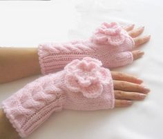 two pink knitted gloves with flowers on the fingers and thumblesss attached to them