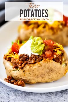 two loaded baked potatoes on a white plate with sour cream and toppings, ready to be eaten