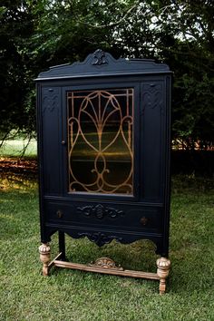 an old fashioned black cabinet sitting in the grass