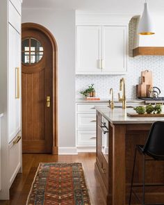 a kitchen with white cabinets and wooden flooring next to a counter top on an area rug