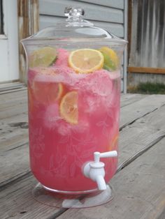 a pitcher filled with ice and lemons on top of a wooden table next to a building