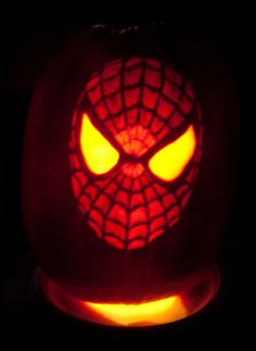 a pumpkin carved to look like a spider - man with eyes glowing in the dark