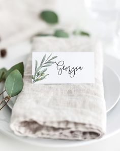 a place setting with napkins and greenery on the table for guests to eat