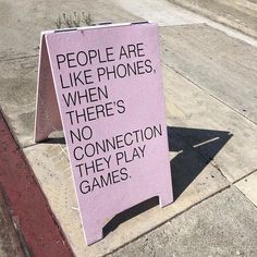 a pink sign sitting on the side of a road next to a sidewalk with people are like phones, when there's no connection they play games