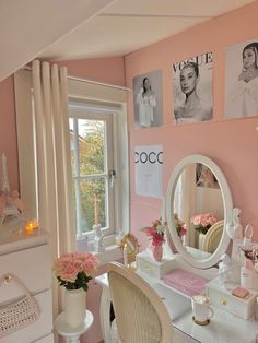 a bedroom with pink walls and pictures on the wall, including a vanity table in front of a window