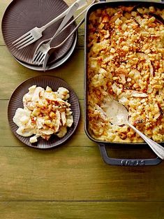 a casserole dish with chicken and rice in it on a wooden table next to two plates