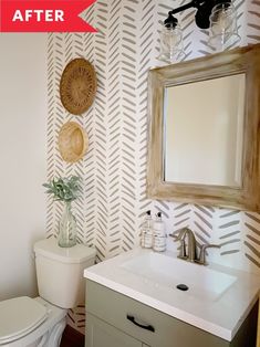 a bathroom with a white toilet sitting next to a sink under a mirror and a wooden framed mirror