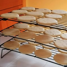 some cookies are cooling on a rack in front of an orange wall and white tile floor