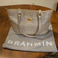 Brahmin's Medium Asher Tote Is A Lightweight Bag With Plenty Of Interior Space. This Structured Style Is Polished And Practical, Featuring Brahmin's Signature Organizational Details. Featured In A Chic Pearlized Neutral Grey. Genuine Leather. Very Good Condition Medium Zip Top Tote Double Adjustable Handles Front Slide In Pocket Footed Bottom Interior Zip Pocket Two Organizer Pockets Dust Bag Included 15" Wide, 10" High, 4.5" Deep, 10" Handle Drop Classic Silver Bags With Gold-tone Hardware, Elegant Silver Bags, Brahmin Bags, Lightweight Bag, Slide In, Zip Top, Womens Tote Bags, Zip Pockets, Dust Bag