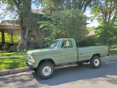 an old pick up truck parked on the side of the road in front of a house