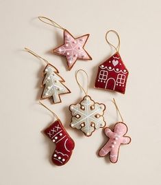 christmas ornaments are hanging from strings on a white surface, including gingerbreads and snowflakes