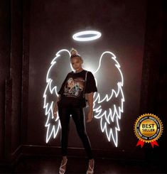 a woman standing in front of a neon angel sign