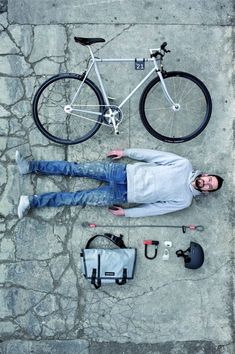 a man laying on the ground next to a bicycle and other items that include an umbrella