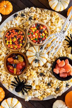 a plate filled with popcorn, candy and candies next to other halloween foods on a table