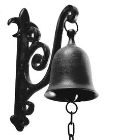 an old fashioned bell hanging from the side of a metal wall mounted light with a chain attached to it