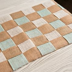 a brown and blue checkered blanket sitting on top of a wooden floor next to a bed