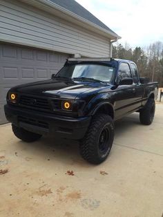 a black truck parked in front of a garage