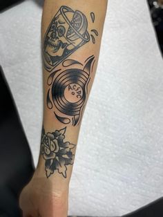 a person with a tattoo on their arm has a record and skull in the background