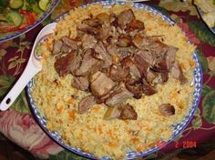 a blue and white plate topped with meat and rice