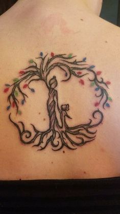 a woman's back with a tree tattoo on it