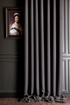 a painting is hanging on the wall next to a drapes with a woman's head